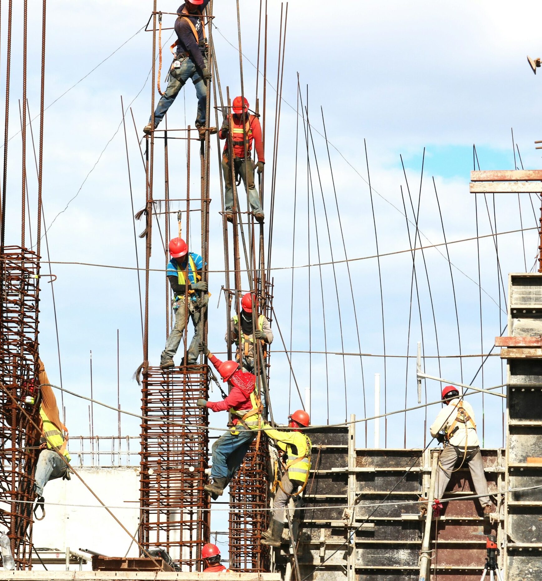 Picture showing workers in safety vests and hard hats climbing an unfinished structure to show an example of situations leading to Construction injury